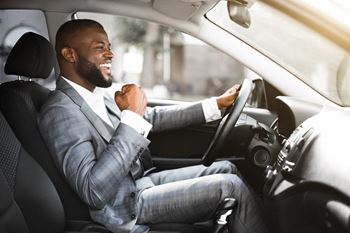Business professional male in gray suit excited while driving car.